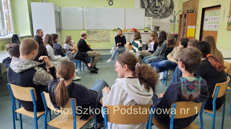 grupa uczniów siedzi w klasie na krzesełkach ułożonych w okrąg